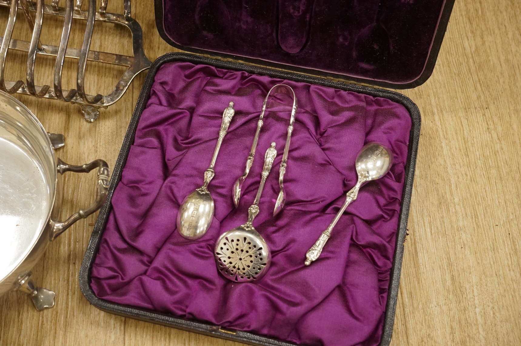 A quantity of assorted plated wares, including flatware, a tea caddy, a chatelaine, a toast rack, a sauceboat, a butter dish and a pair of candlesticks, etc.
